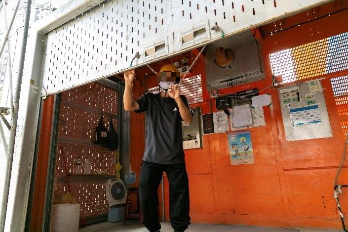 阿順熟練地操控電梯、開闔鐵閘門，確保工地出入人員的安全